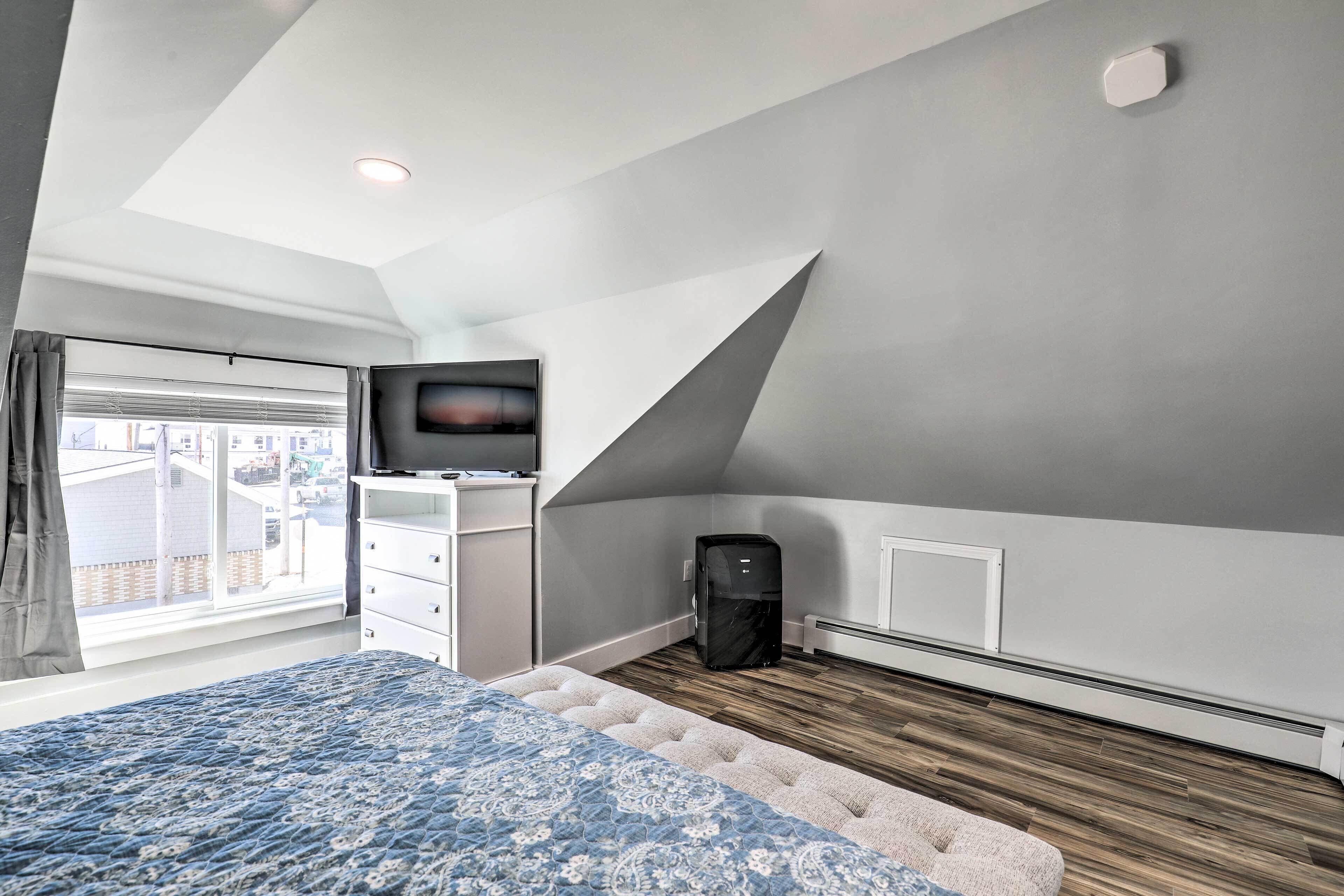 A bedroom with a bed, a television on a stand, a heater, and a window with curtains.