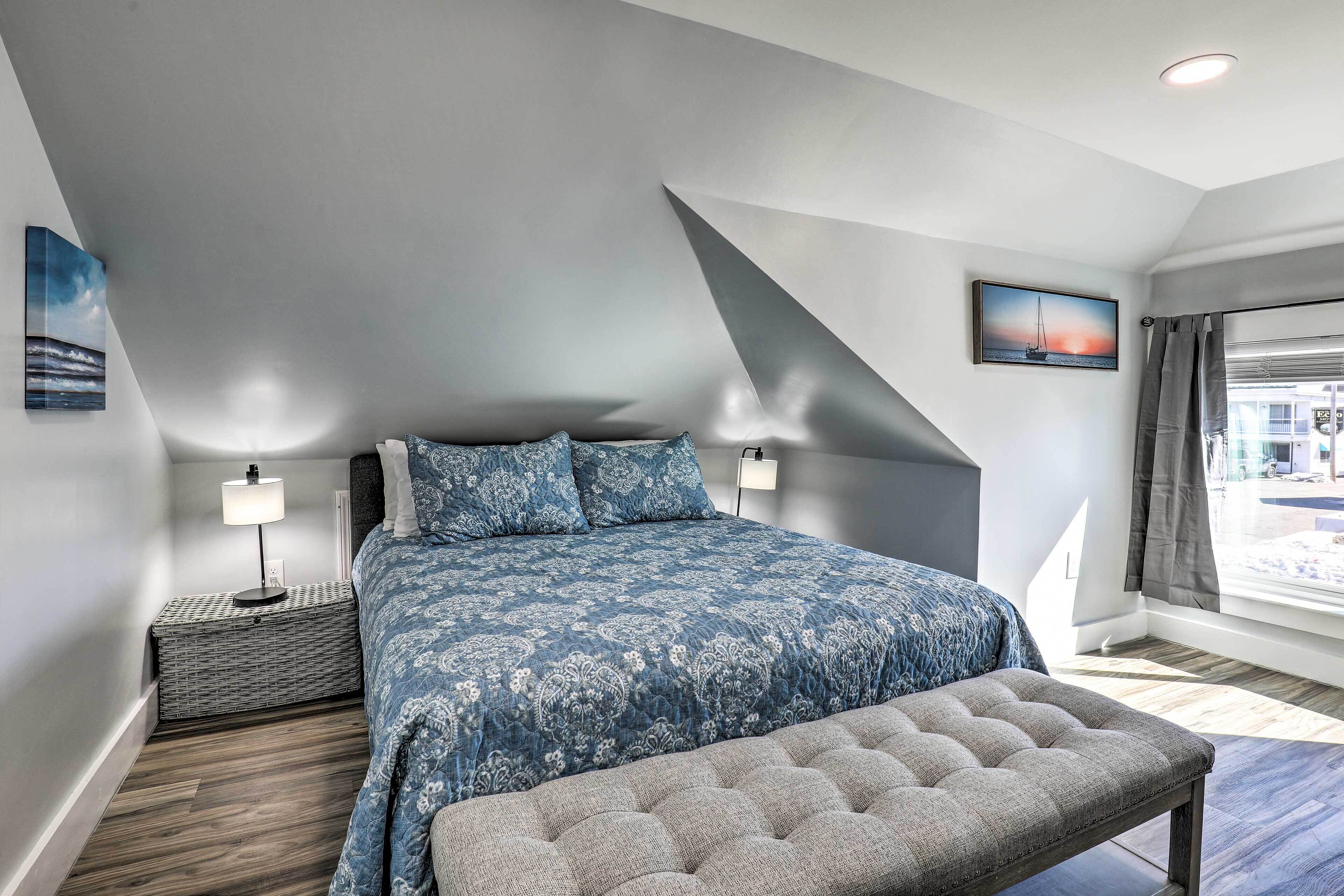A bedroom with a bed, bedside tables, a bench, and a window with curtains.