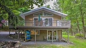 Een chalet met twee verdiepingen, een balkon, een overdekt terras en een vuurkuil van steen.