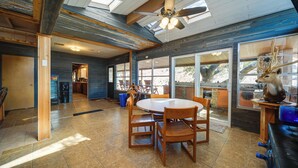 A spacious kitchen with a large dining table, wooden chairs, and a ceiling fan.