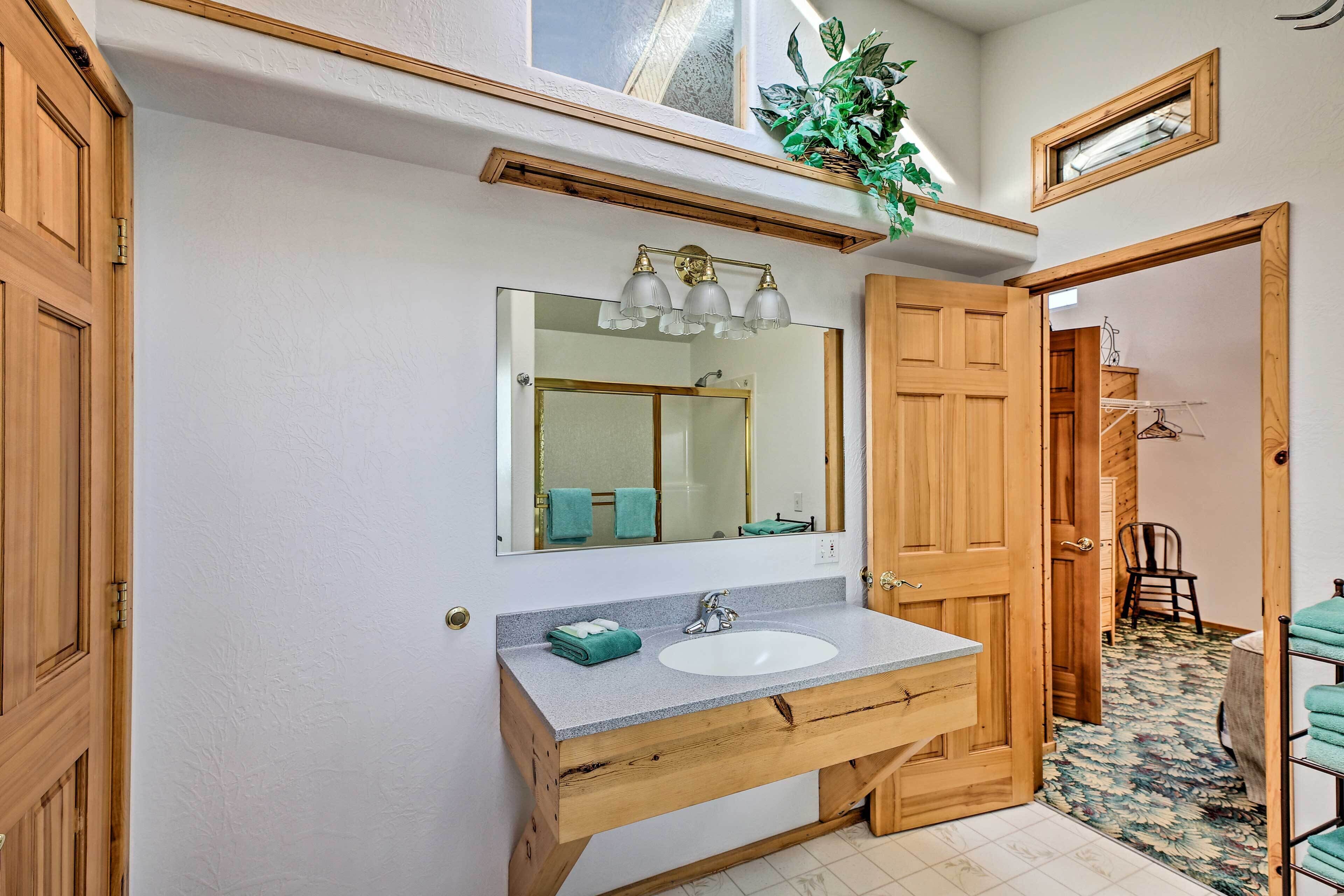 Un baño con tocador de madera, un espejo grande y una ducha.