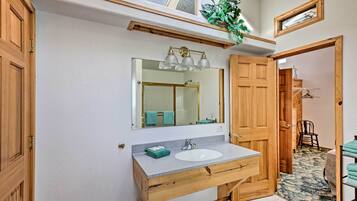 Un baño con tocador de madera, un espejo grande y una ducha.