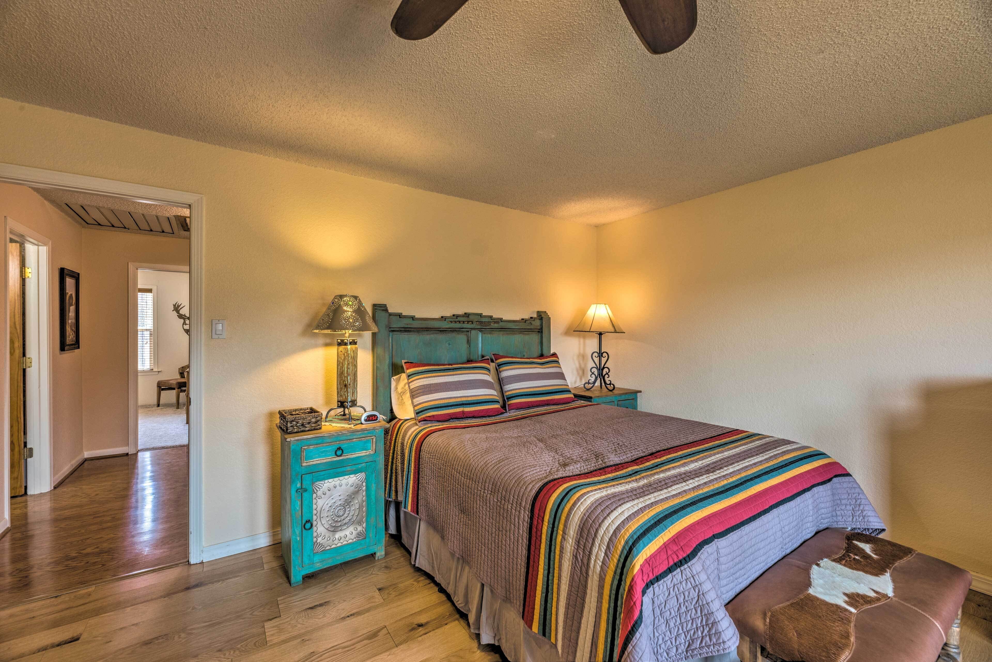 A bedroom with a bed, a nightstand, a lamp, and a wooden floor.