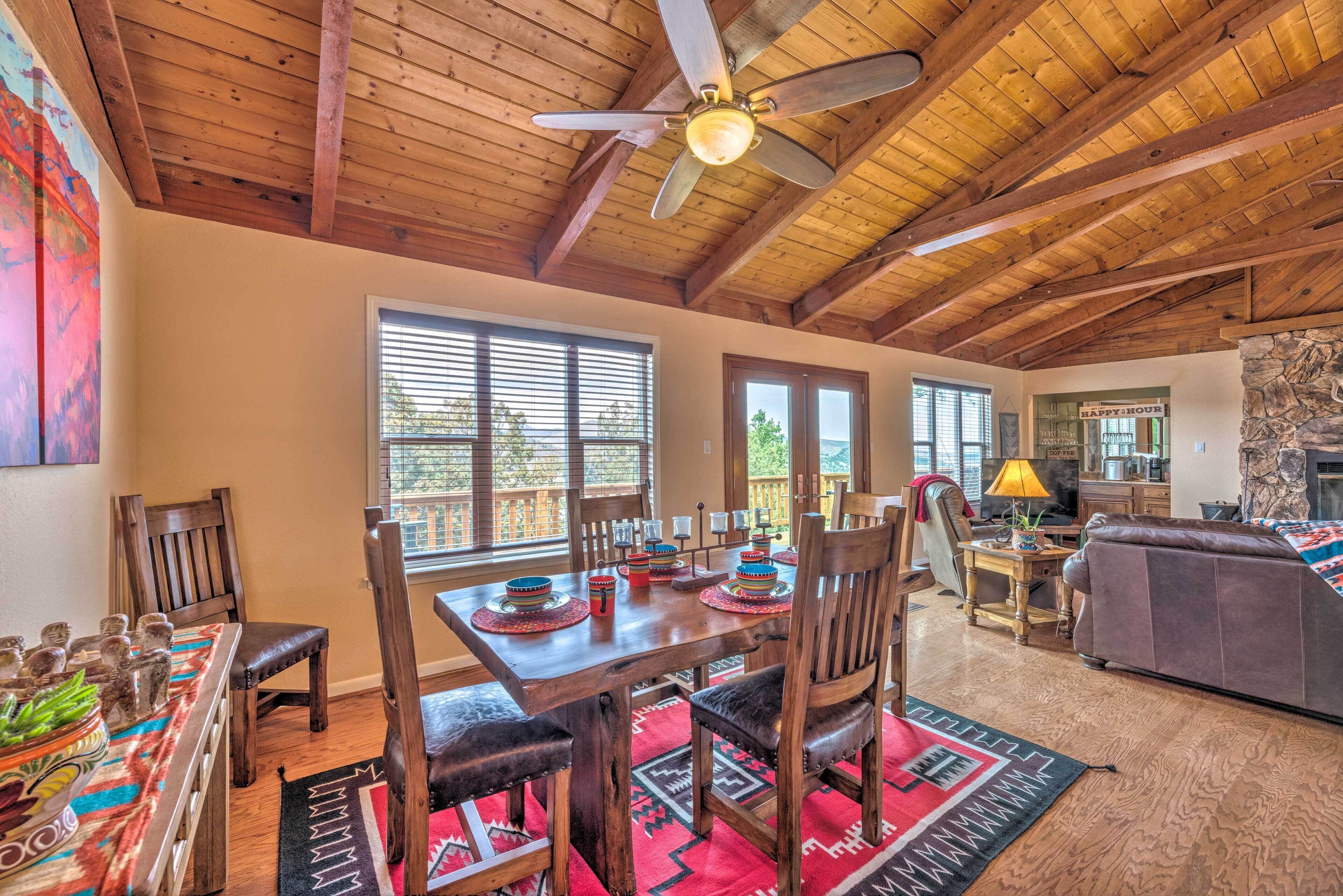 A spacious living room with a wooden ceiling, a dining area with a wooden table and chairs, and a cozy seating area with a couch.