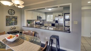 Une cuisine moderne avec des armoires blanches, un comptoir en granit et des appareils électroménagers en acier inoxydable.