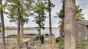 Une terrasse en bois menant à un quai au bord d’un lac, entourée de grands arbres.