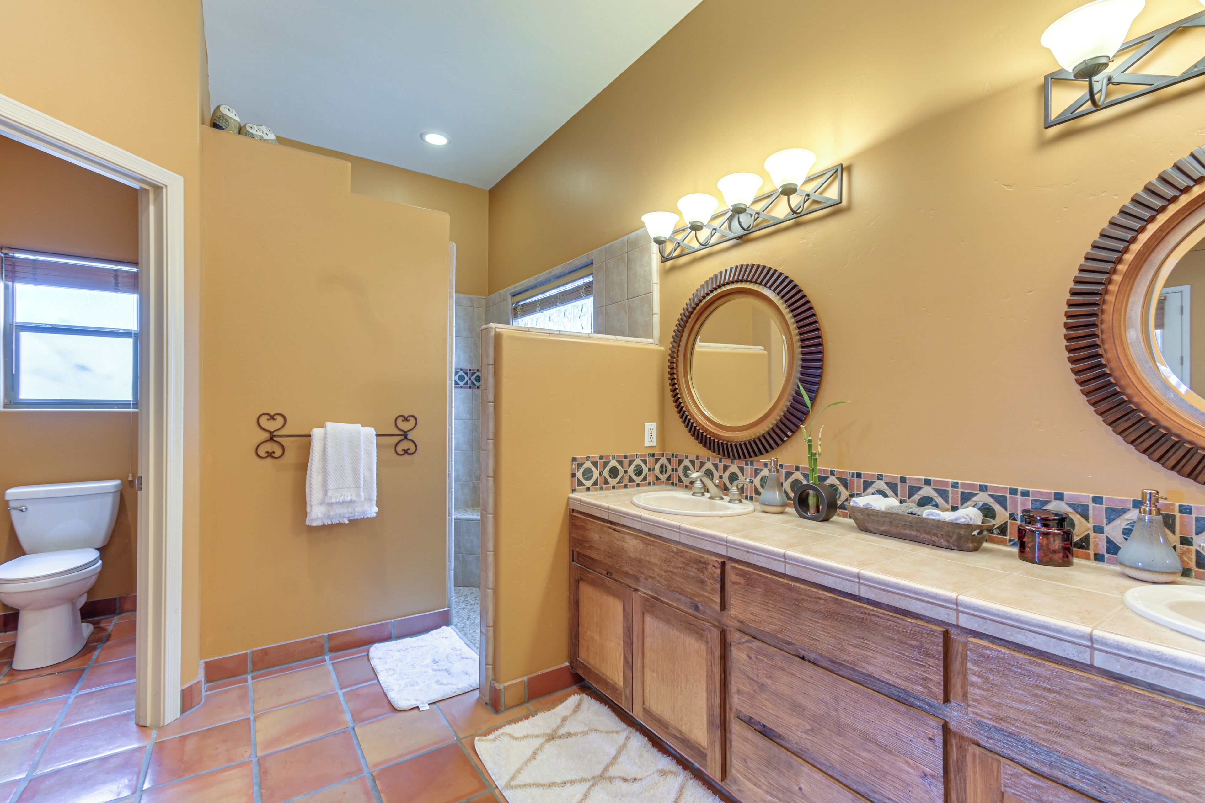 Une salle de bain comprenant des toilettes, un lavabo, un meuble-lavabo et un miroir.