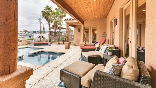 A covered outdoor area with a pool, wicker furniture, and a view of the surrounding landscape. - Private Pool, Spa, & Grills: Lake Havasu City Home (Lake Havasu City)