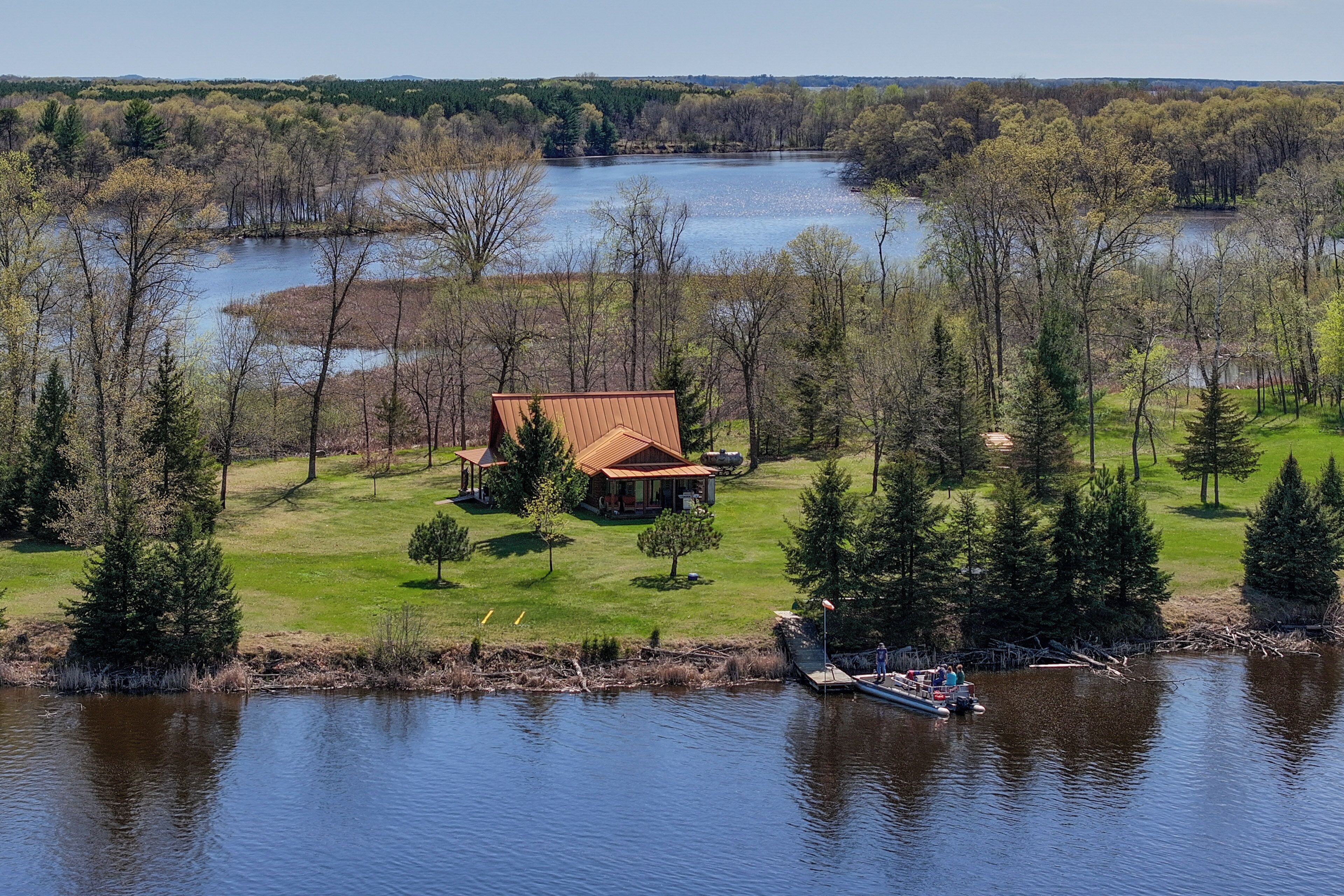 Propiedad frente al lago con una casa, muelle y bosque circundante.