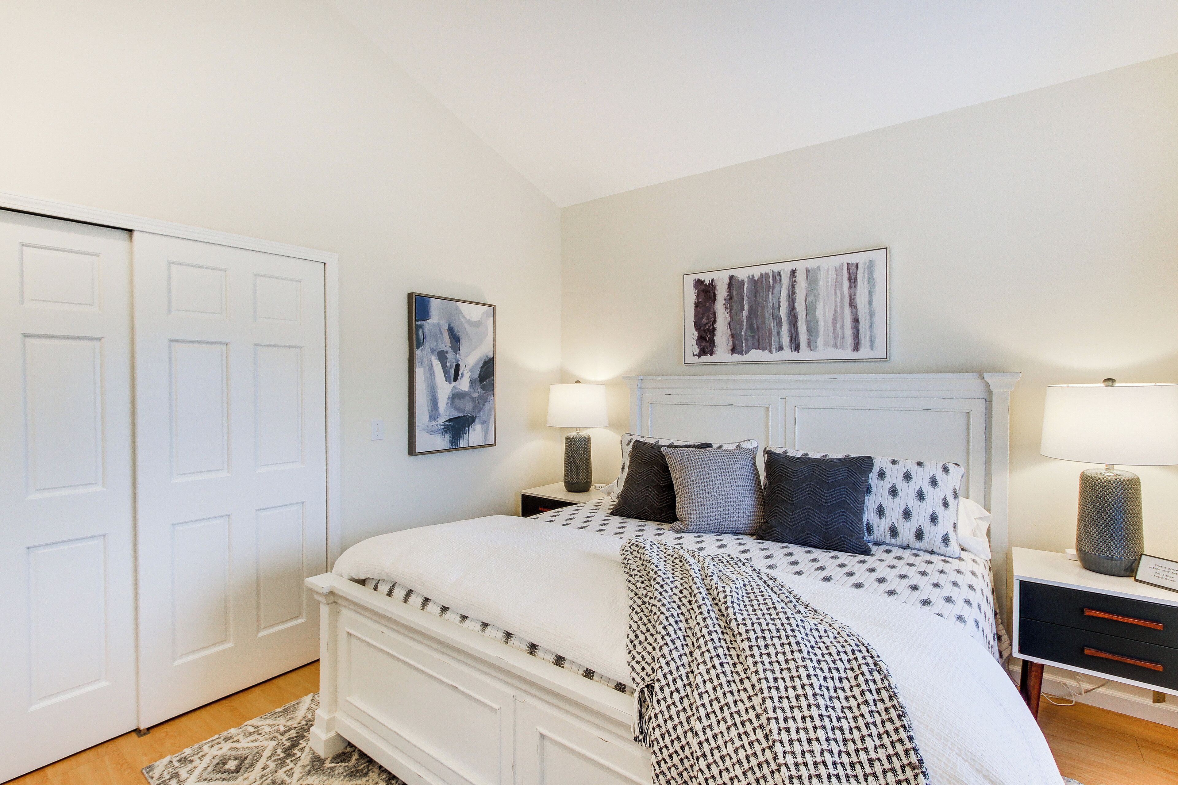 A bedroom with a bed, bedside tables, and artwork on the walls.