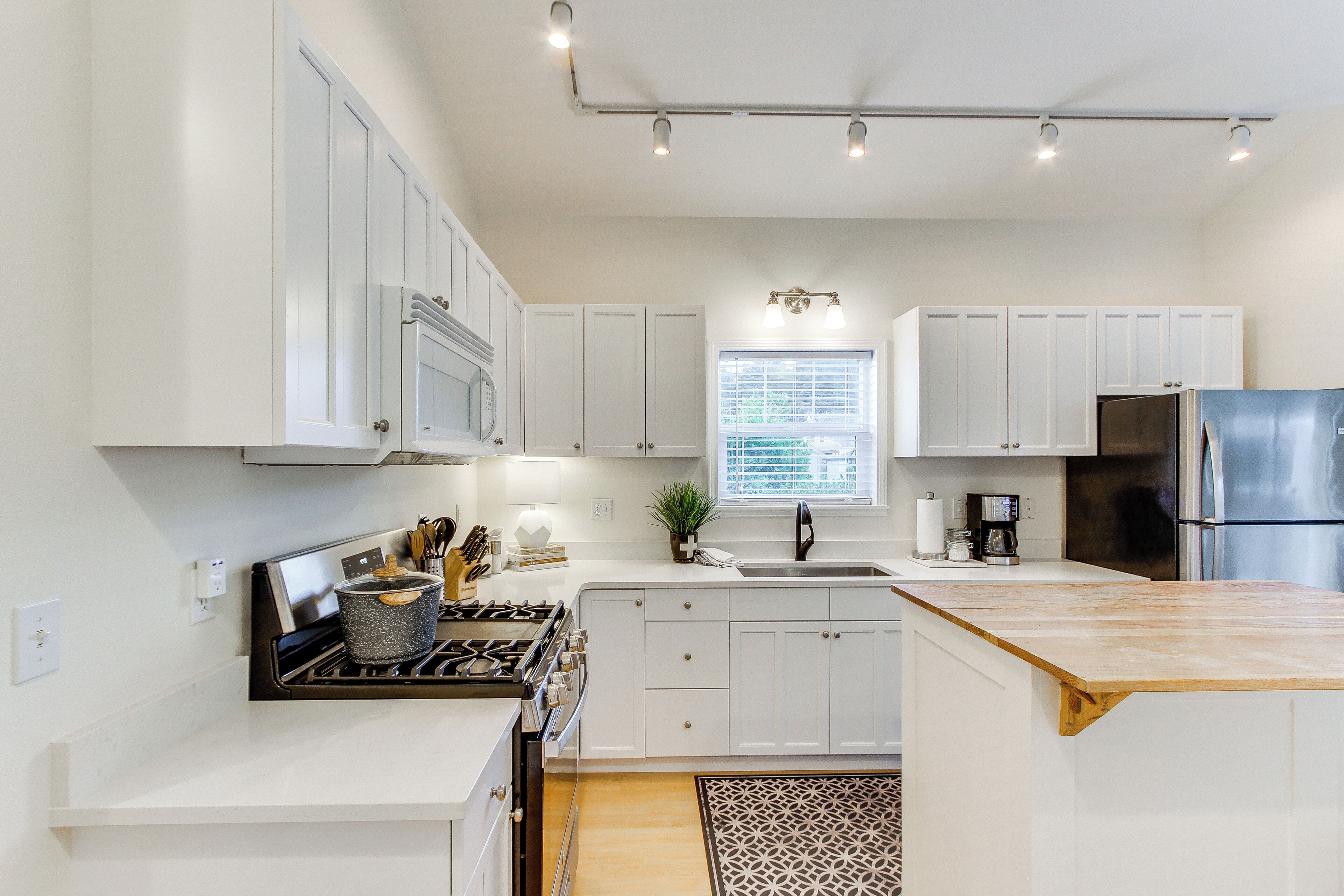 A modern kitchen with white cabinets, a stainless steel refrigerator, and a built-in oven.