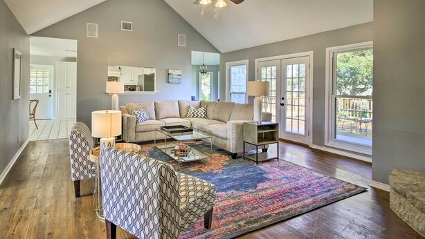 A spacious living room with a high ceiling, a ceiling fan, a large window, and a patterned rug. - Downtown Boerne Home on Cibolo Creek w/ Fire Pit (Boerne)