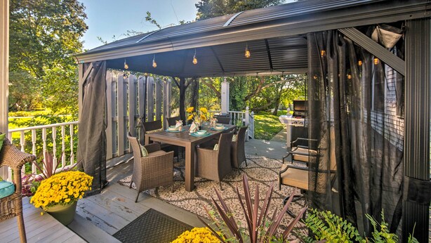 Une terrasse extérieure dotée d’un espace salon abrité, d’une table à manger et de chaises.