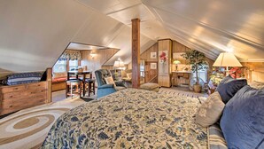 Une chambre confortable située sous les toits, avec un grand lit, des meubles en bois et un plafond en pente.