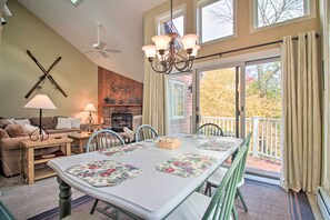 A dining area with a table set for four, a ceiling fan, and a fireplace in the background. - Ski-in Ski-out Okemo Oasis w/ Deck + Mtn View! (Ludlow)