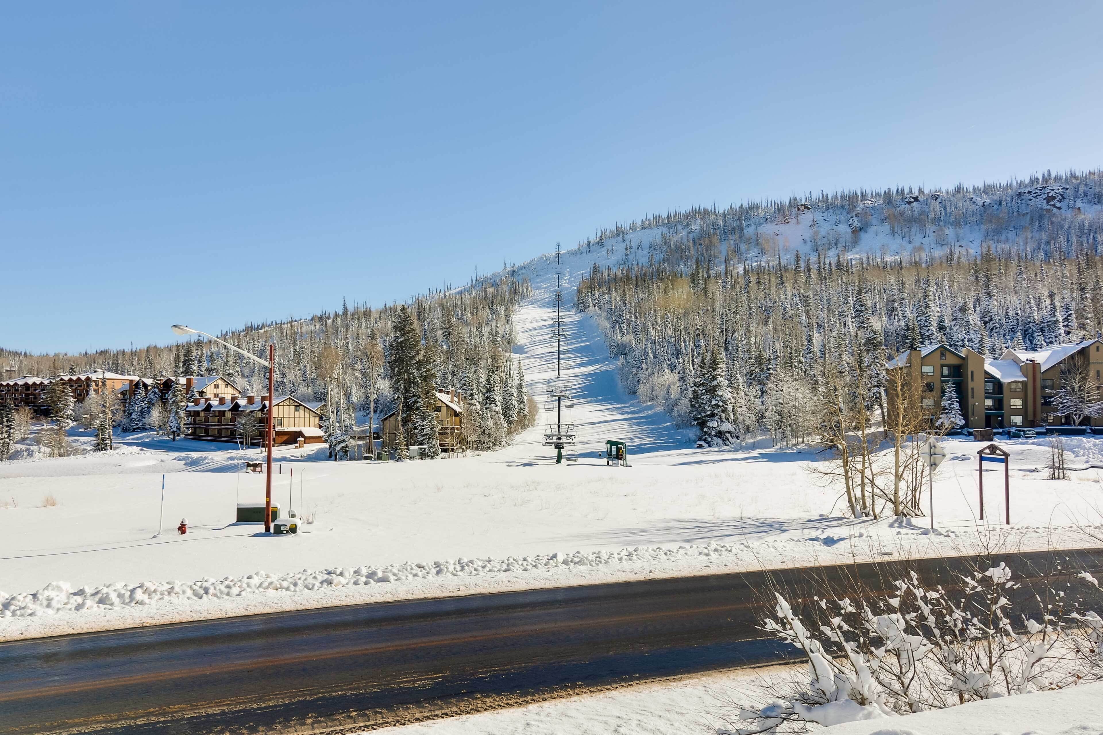 A snow-covered landscape with a road, buildings, and a ski slope.