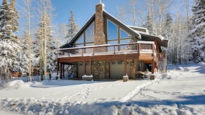A lodge with a stone chimney, wooden deck, and snow-covered surroundings. - Group Ski Getaway Near the Base of Chairlift 8! (Brian Head)