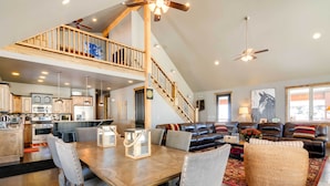 A spacious living area with a dining table, a sofa set, and a staircase leading to an upper level. - Group Ski Getaway Near the Base of Chairlift 8! (Brian Head)