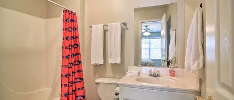 A bathroom with a bathtub, toilet, sink, and a mirror above the sink.
