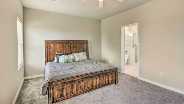 Une chambre à coucher avec un lit en bois, un ventilateur de plafond et une porte donnant sur une salle de bain.