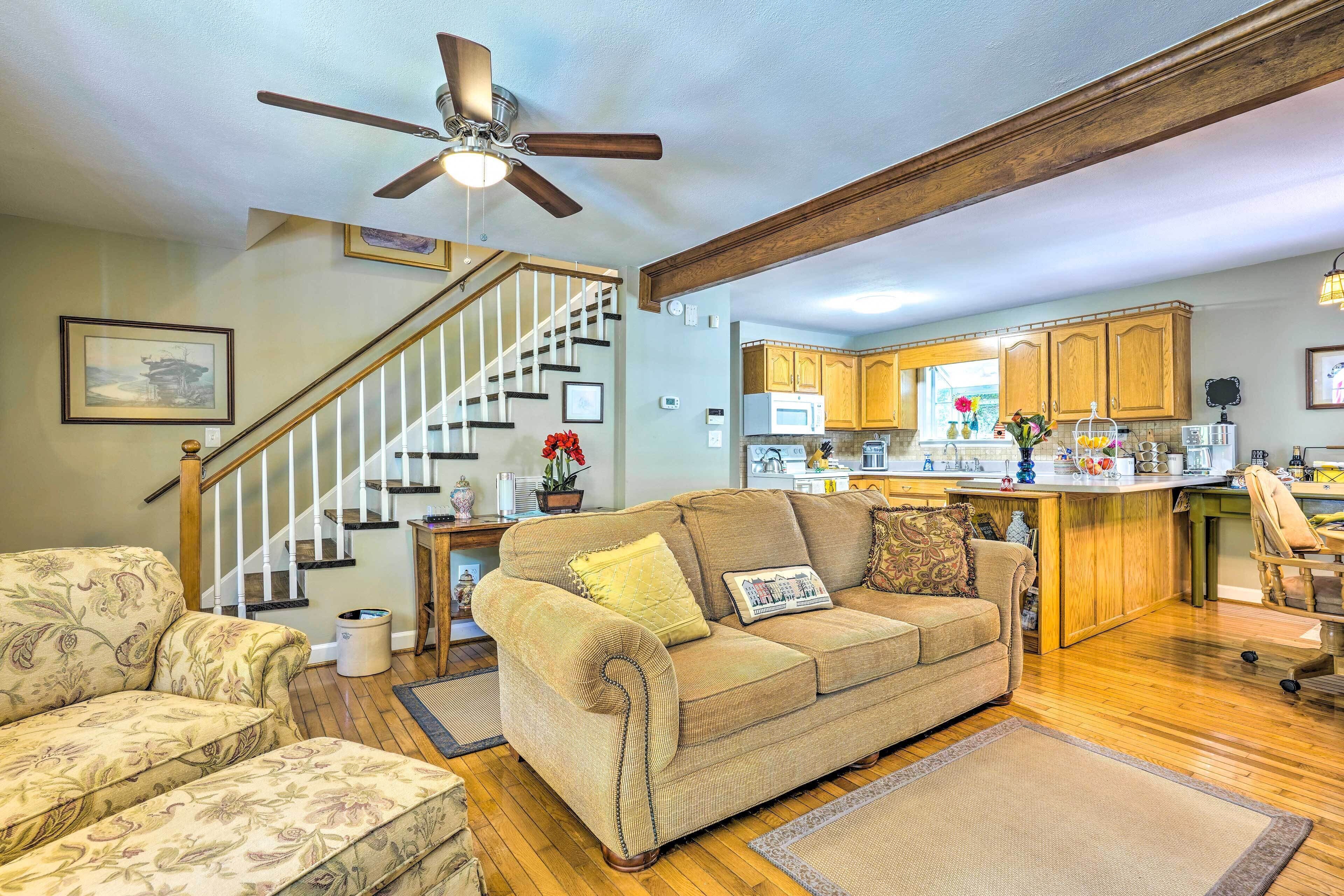 A spacious living room with a sofa, a coffee table, and a dining area with wooden cabinets and a kitchen in the background.