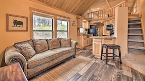 A cozy living room with a sofa and a wooden staircase leading to an upper level. - Pagosa Springs Tiny Cabin: Fish, Hike, Ski & Soak! (Pagosa Springs)