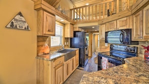 A kitchen with wooden cabinets, granite countertops, a black refrigerator, a microwave, and an oven. - Pagosa Springs Tiny Cabin: Fish, Hike, Ski & Soak! (Pagosa Springs)