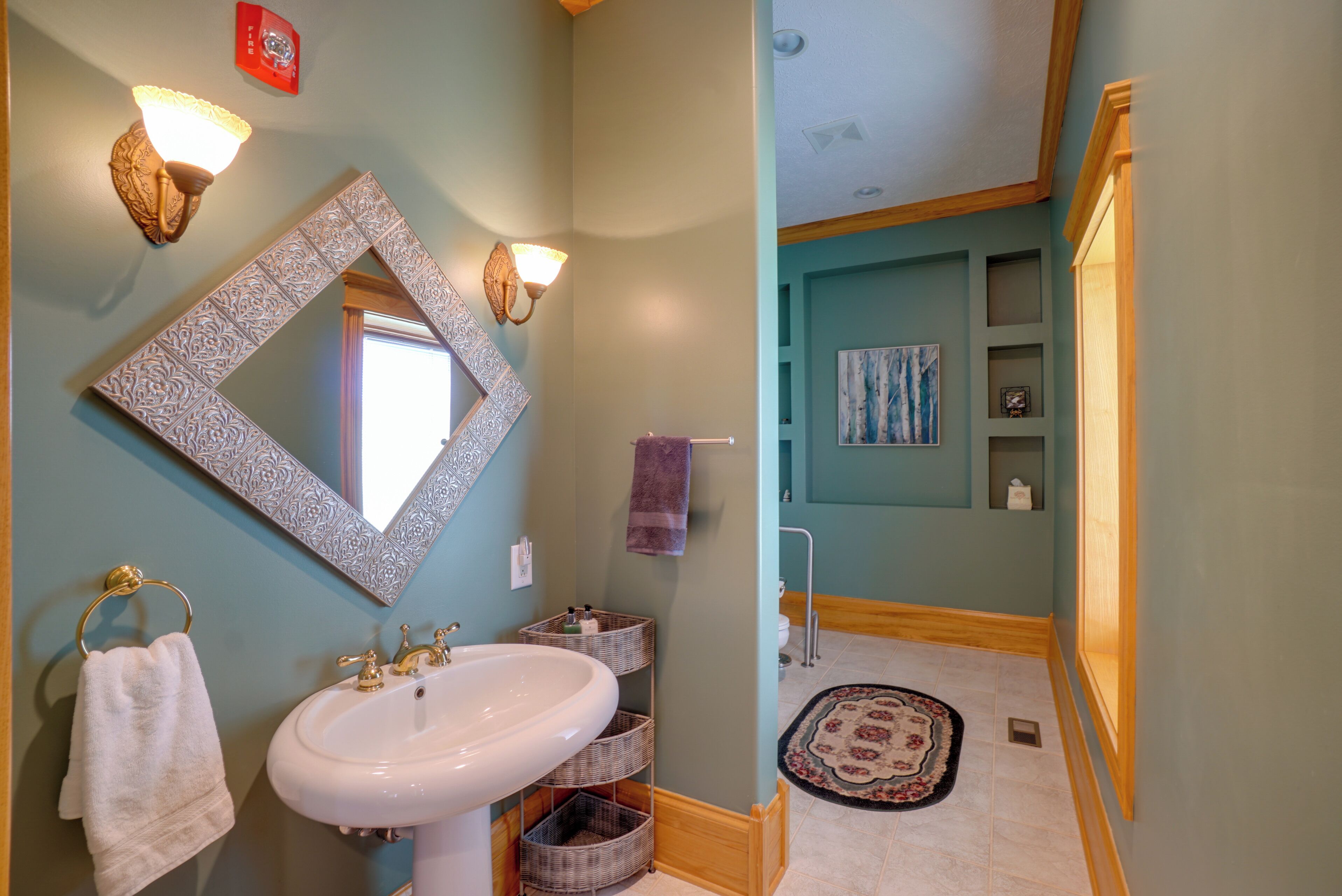 A bathroom with a large mirror, a sink, and two wall sconces.
