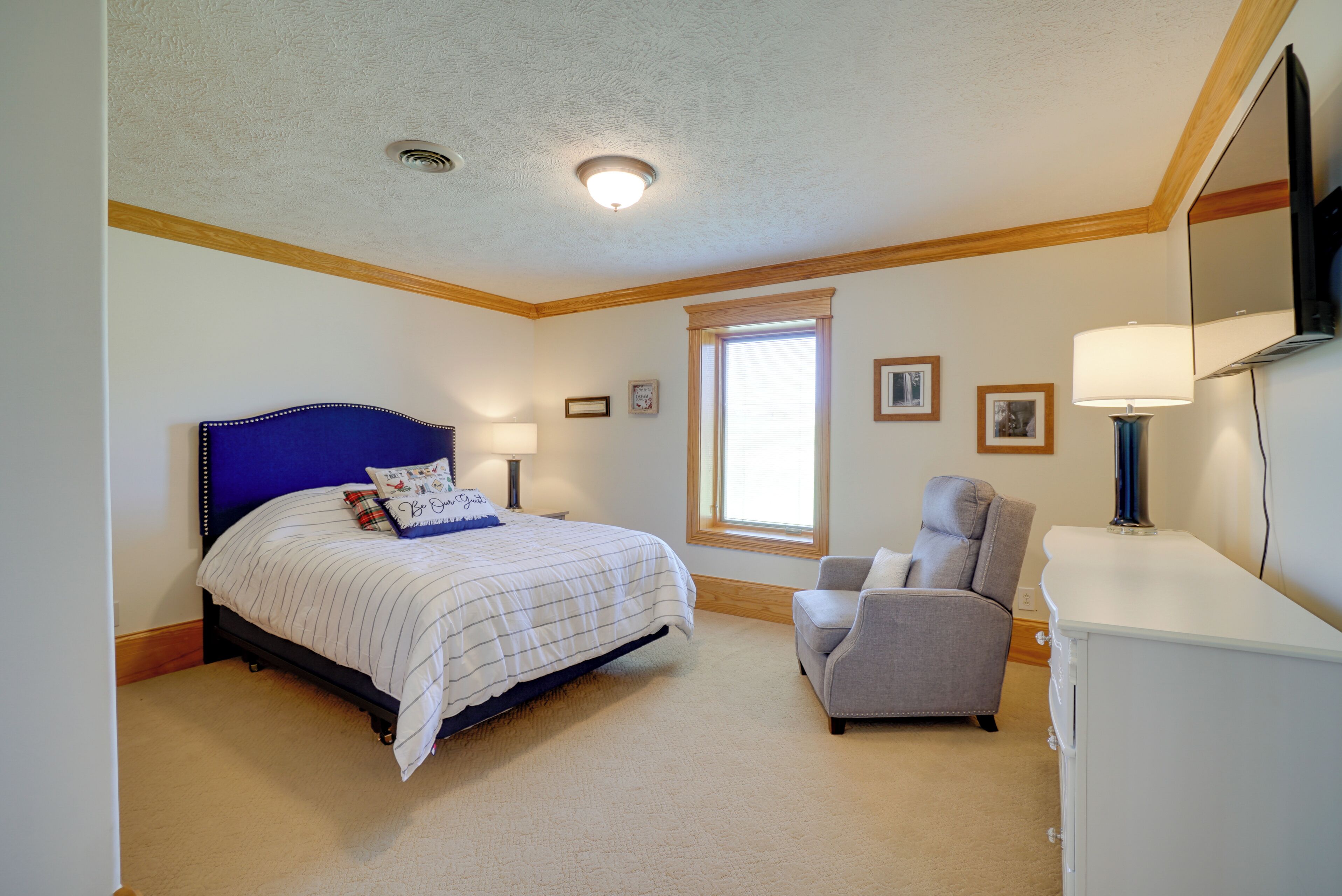 A bedroom with a bed, a chair, a desk, and a window.