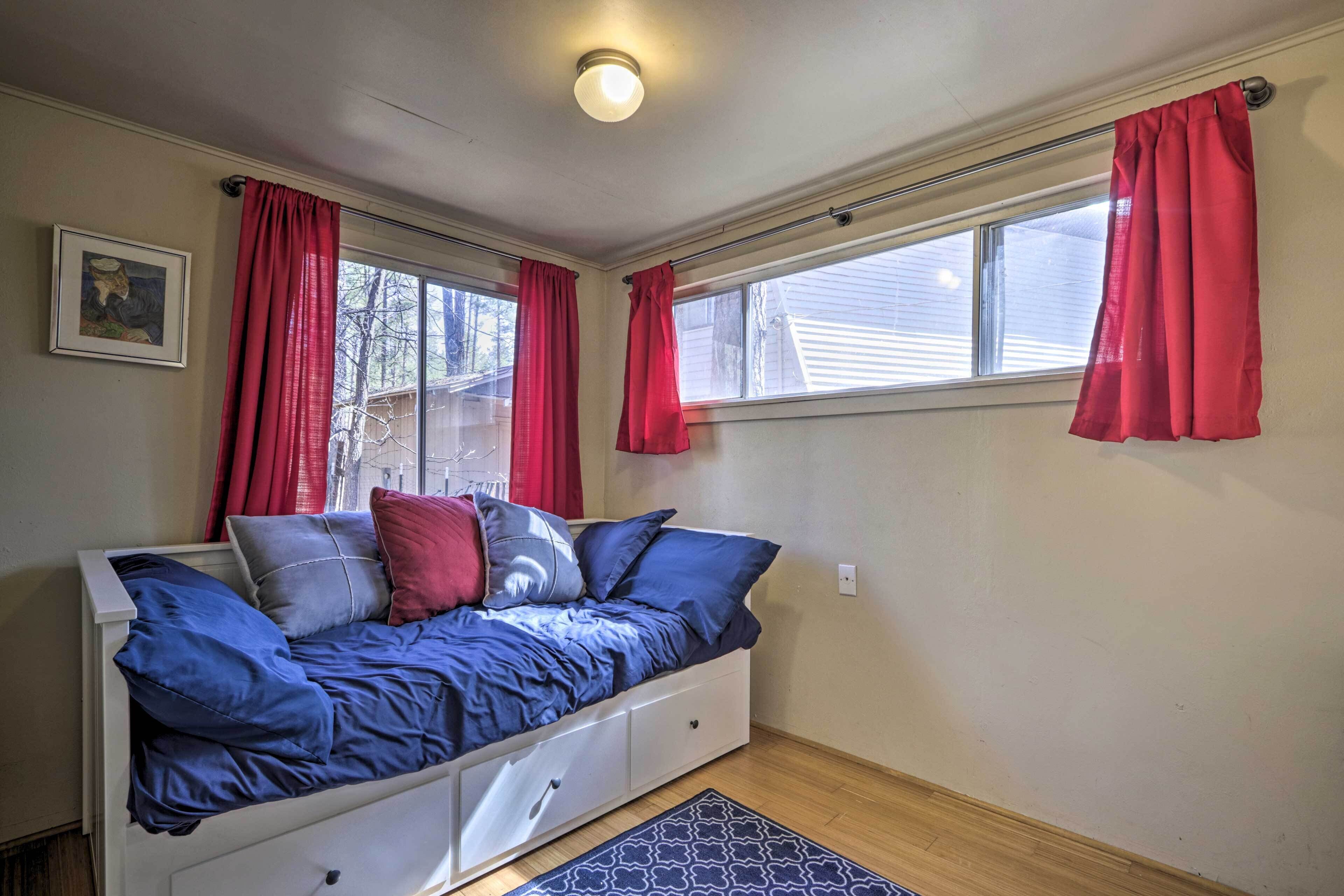 A bedroom with a bed, a window, a picture on the wall, and a ceiling light.