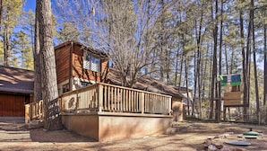 A cabin with a deck, surrounded by tall trees. - Near Tonto National Forest: Dog-friendly Cabin! (Payson)
