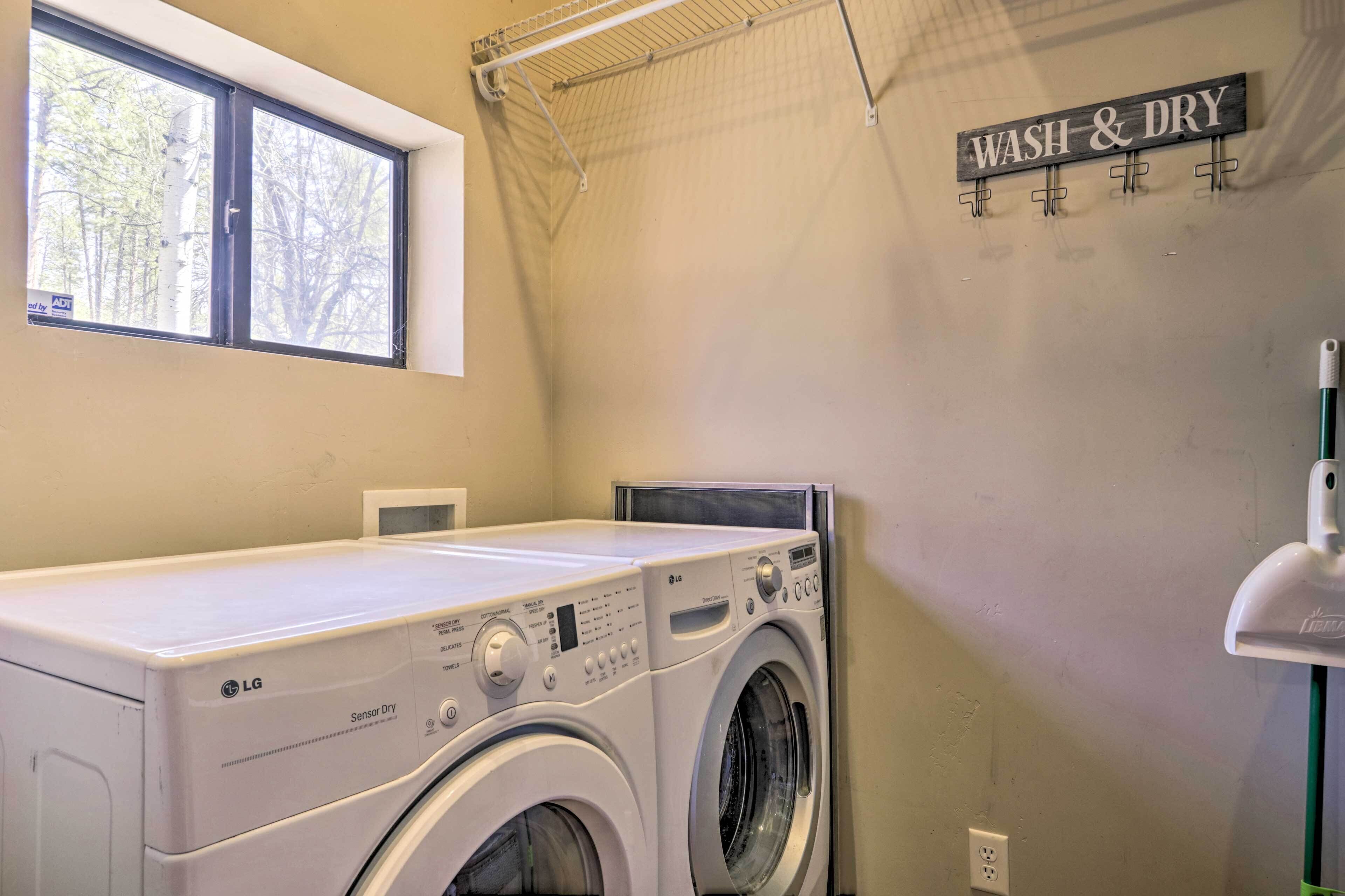 Een wasruimte met een wasmachine, een droger, een raam en een bord met de tekst 'WASH & DRY'.
