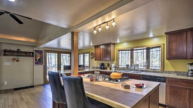 A spacious kitchen with a central island, wooden cabinets, and a large window providing natural light. - Near Tonto National Forest: Dog-friendly Cabin! (Payson)