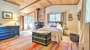 Une chambre confortable avec un grand lit, une commode, une valise et une cheminée.