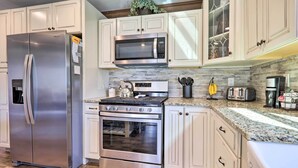A kitchen with stainless steel appliances, white cabinetry, and a granite countertop. - Quaint Creekside Cottage w/ Porch & Backyard! (Lexington)