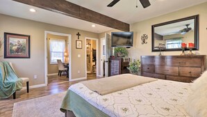 A bedroom with a large bed, a dresser, a TV, and a ceiling fan. - Quaint Creekside Cottage w/ Porch & Backyard! (Lexington)