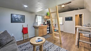 Un espacio habitable compacto con kitchenette, comedor y zona de estar con sofá y una mesita redonda.