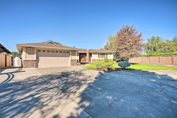 A single-story house with a garage, a front lawn, and a large tree.