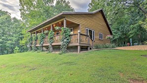A wooden cabin with a porch, surrounded by a grassy yard and trees. - Beautiful Makanda Cabin in Shawnee National Forest (Makanda)