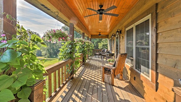 A wooden deck with a ceiling fan, outdoor furniture, and a view of a garden. - Beautiful Makanda Cabin in Shawnee National Forest (Makanda)