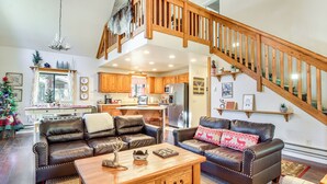 A spacious living room with leather sofas, a wooden coffee table, and a staircase leading to an upper level. - 2 Mi to Fool Hollow Lake: Wooded Cabin w/ Fire Pit (Show Low)