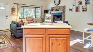 A kitchen with wooden cabinets, a central island, a fireplace, and a dining area with a table and chairs. - 2 Mi to Fool Hollow Lake: Wooded Cabin w/ Fire Pit (Show Low)