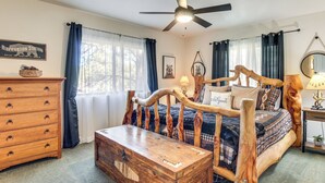 A bedroom with a wooden bed frame, a wooden chest of drawers, a ceiling fan, and a window with curtains. - 2 Mi to Fool Hollow Lake: Wooded Cabin w/ Fire Pit (Show Low)