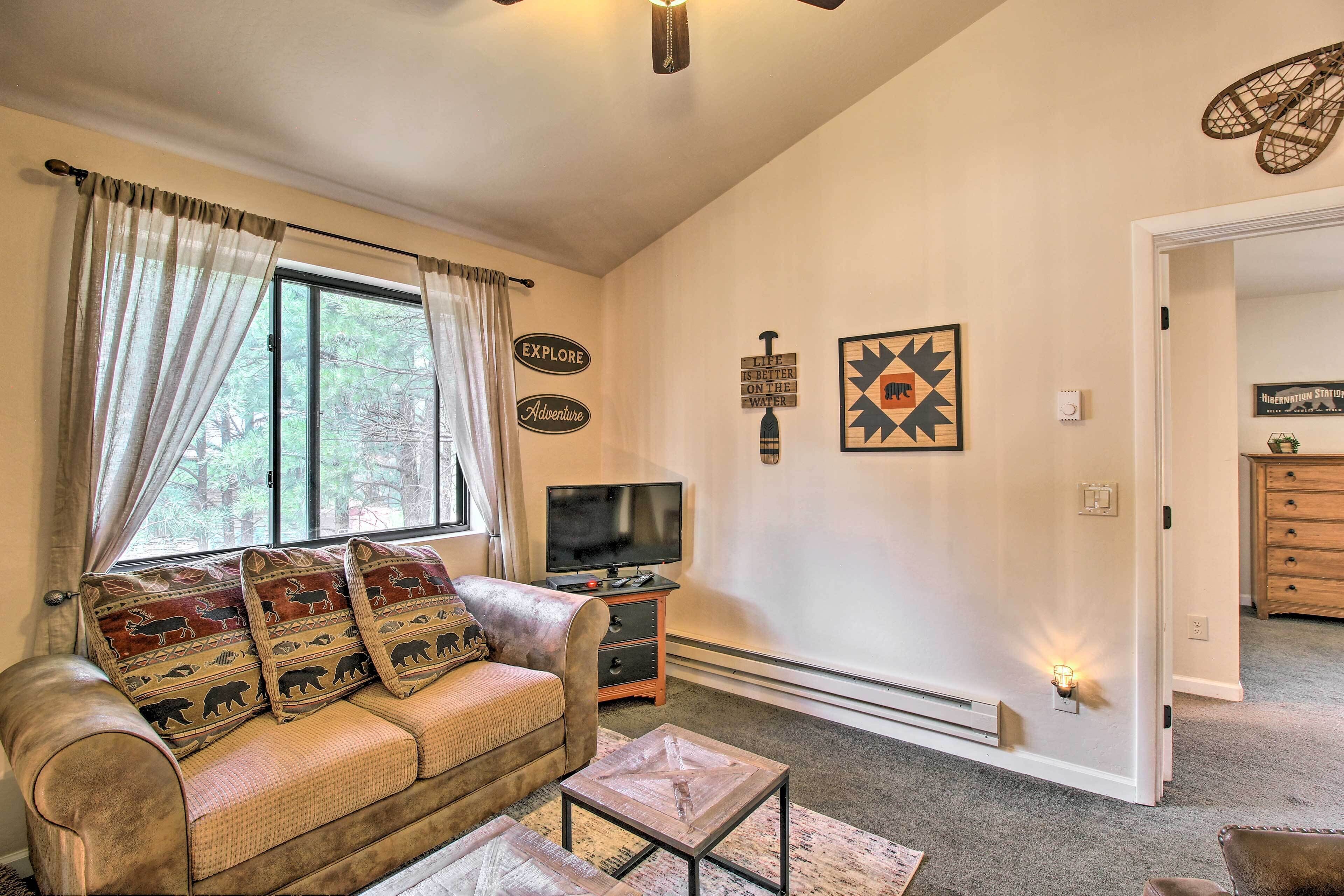 A living room with a sofa, a coffee table, a TV, and wall decorations.