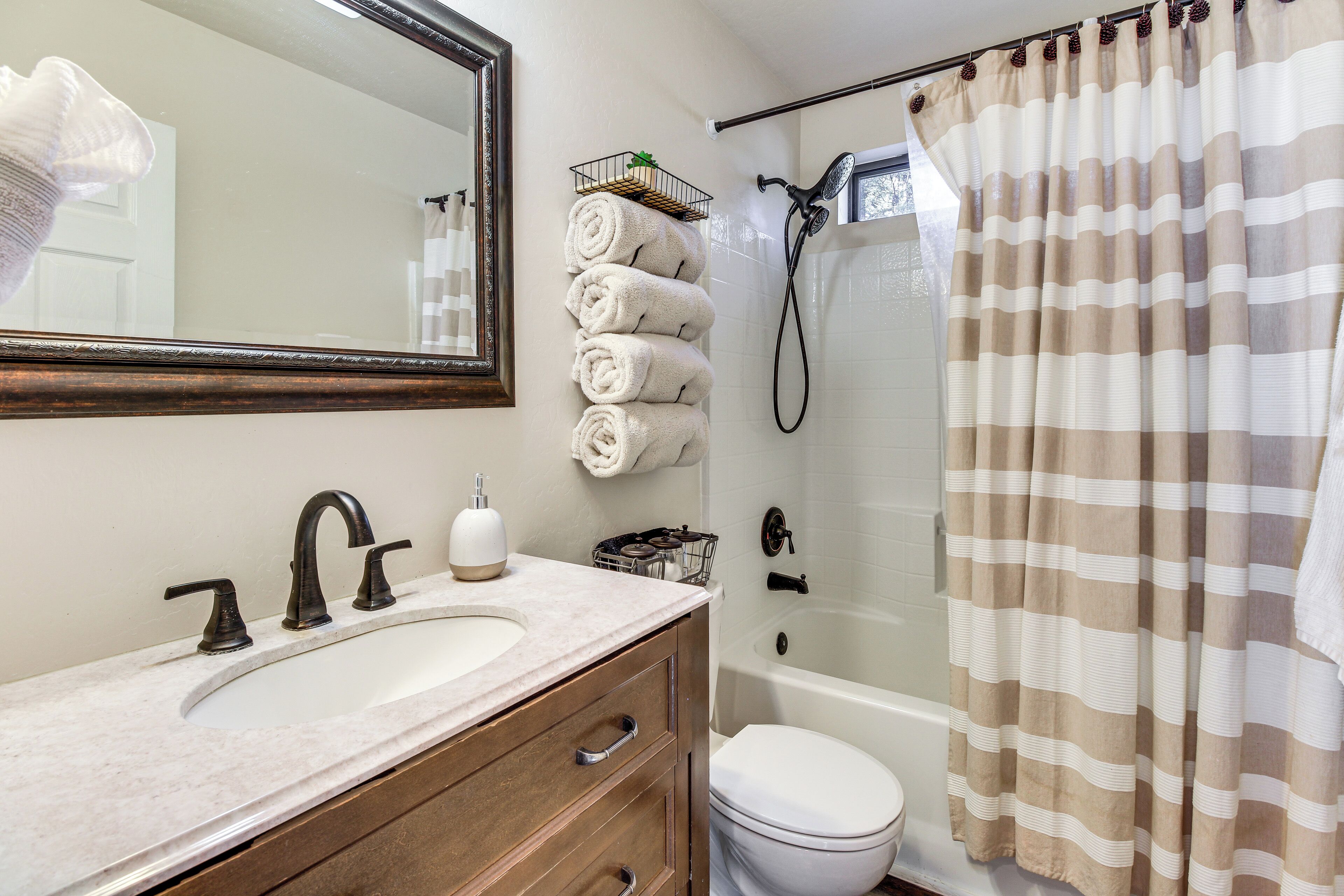 Une salle de bain équipée d’un lavabo, d’un miroir, d’un porte-serviettes et d’un rideau de douche.
