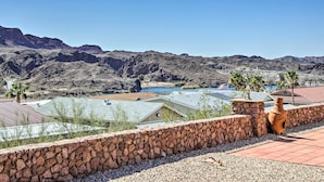 A view of a mountainous landscape with a clear blue sky. There are buildings with flat roofs and a stone wall in the foreground. - Sun-dappled AZ Abode w/ River & Mtn Views! (Parker)