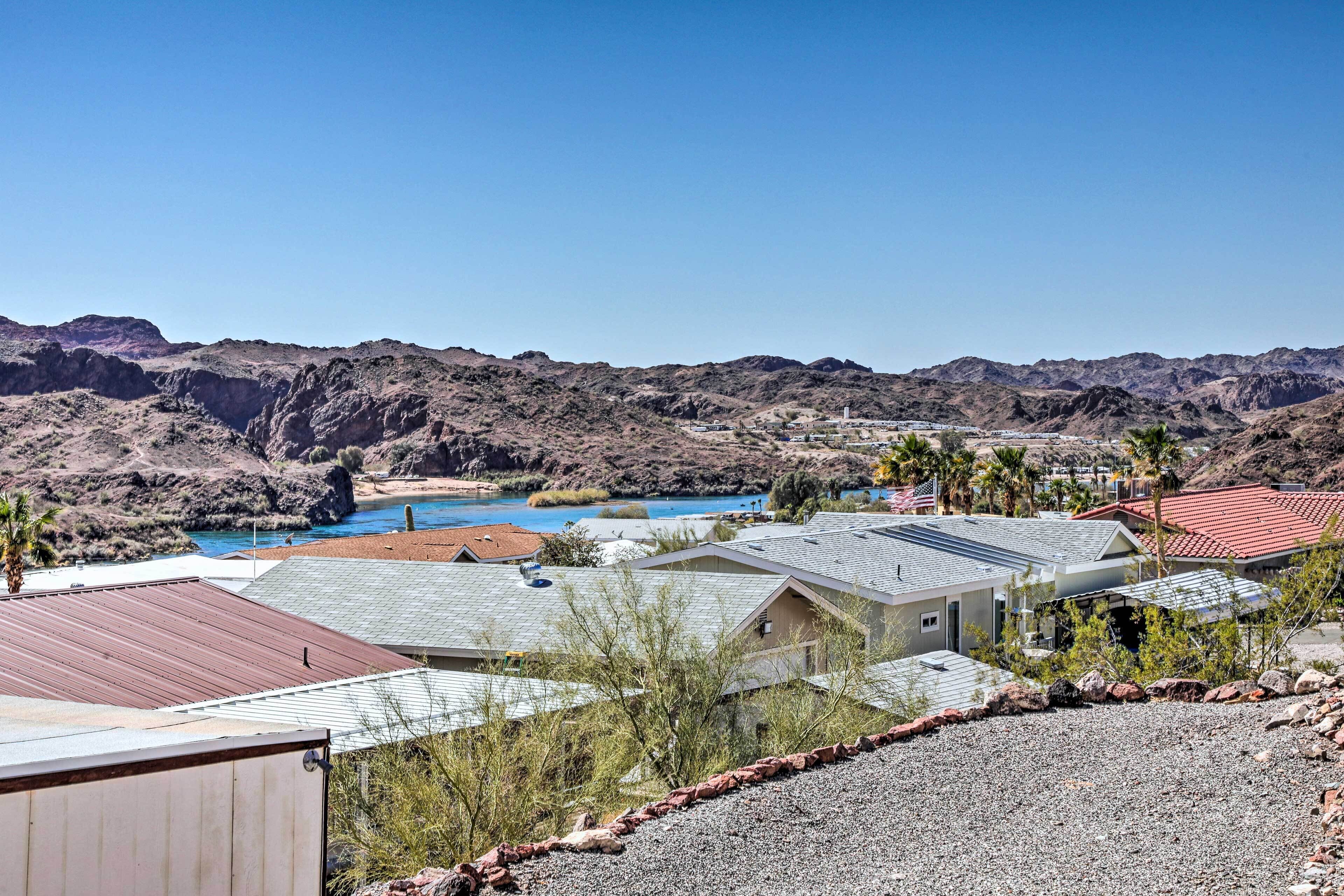 A residential area with houses, a small body of water, and mountains in the background.