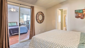 A bedroom with a bed, a circular wall decoration, and a view of another room through a sliding door. - Sun-dappled AZ Abode w/ River & Mtn Views! (Parker)
