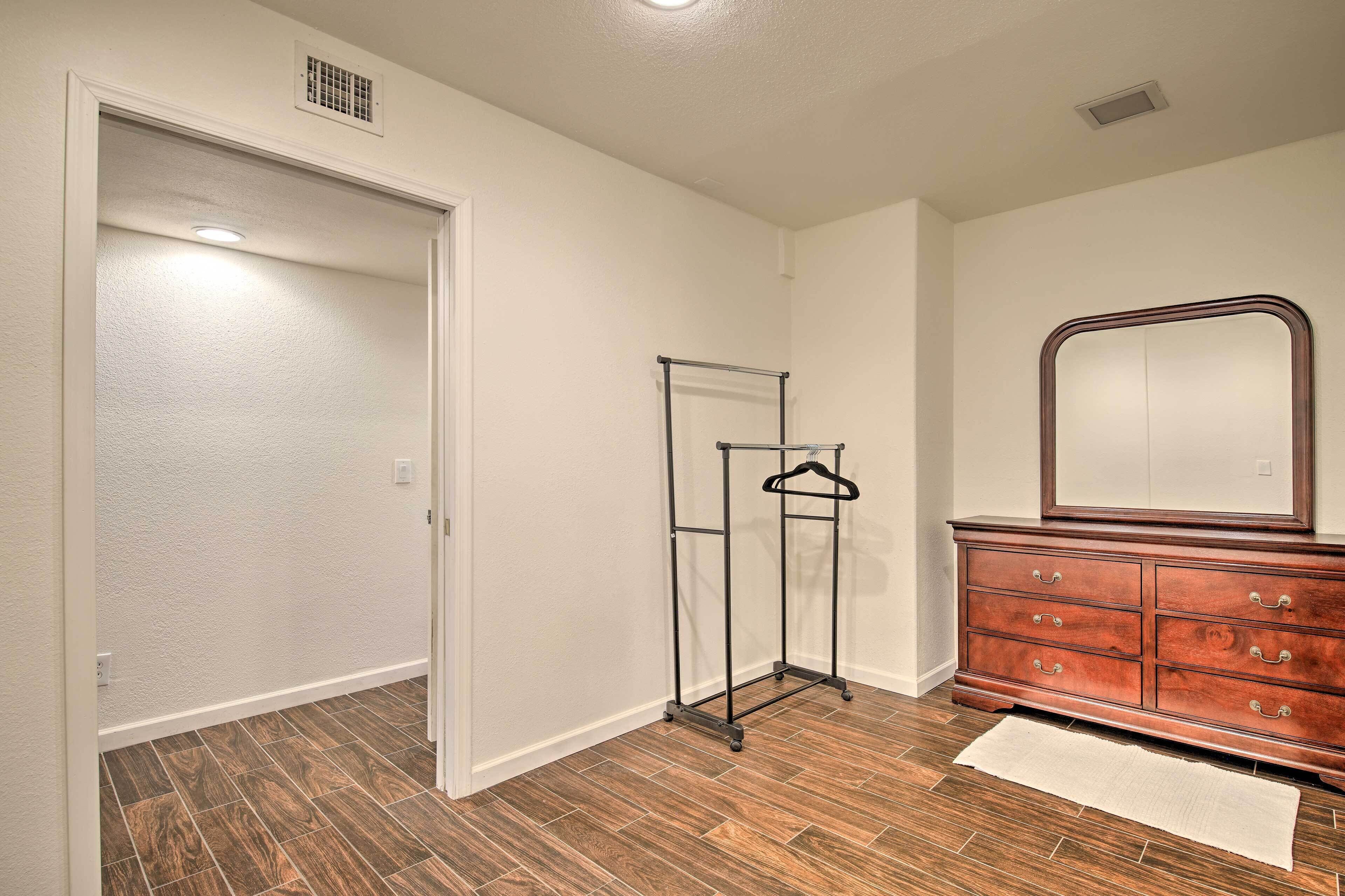 Un couloir avec un plancher en bois, une porte blanche, un porte-manteau et une commode avec des tiroirs.