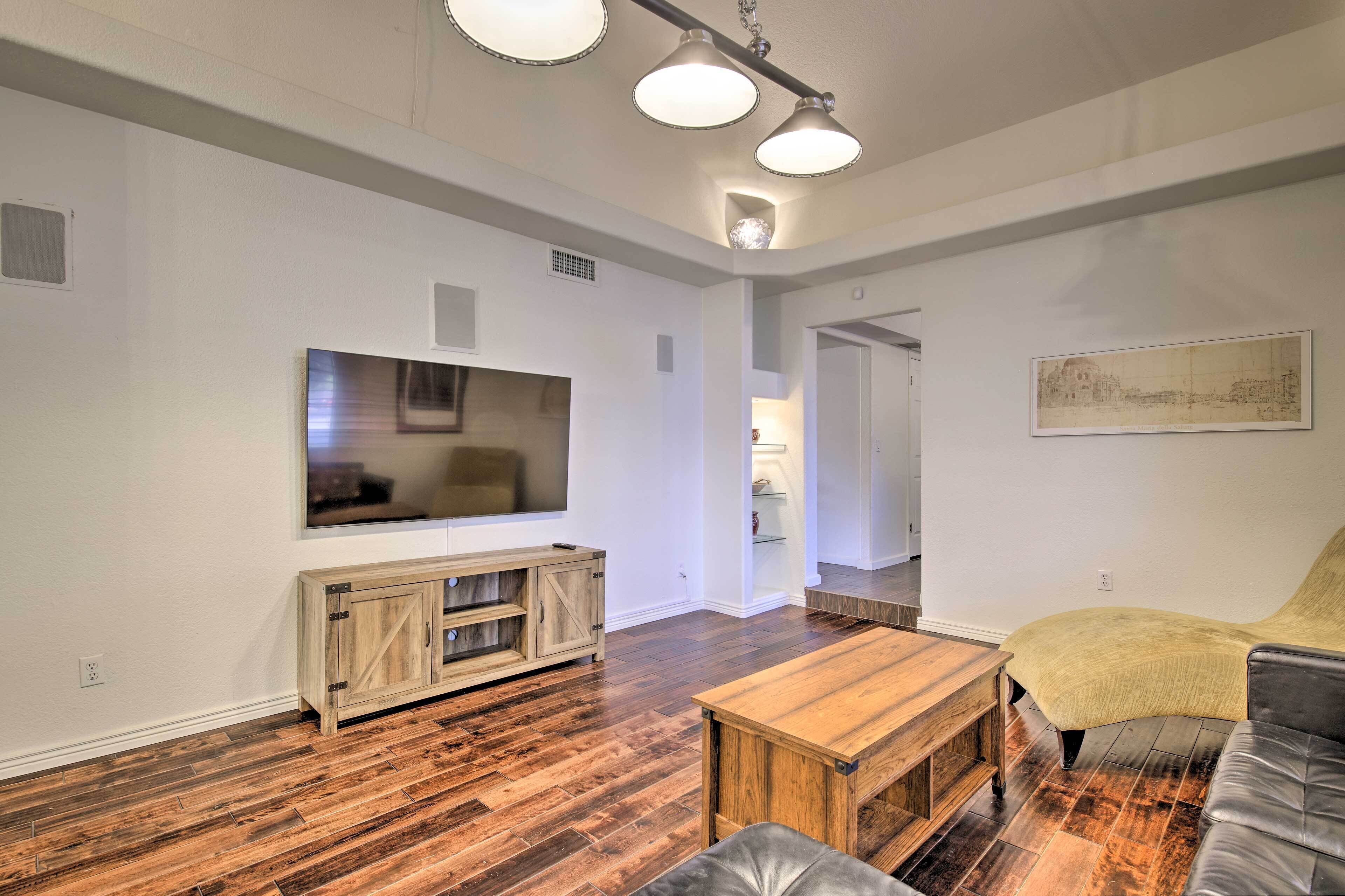 Een moderne woonkamer met houten vloeren, een houten entertainmentsmeubel, een flatscreen televisie, een salontafel en een leren bank.
